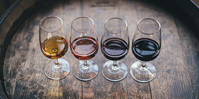 Cuatro copas de vino de distintos colores sobre una superficie de madera.