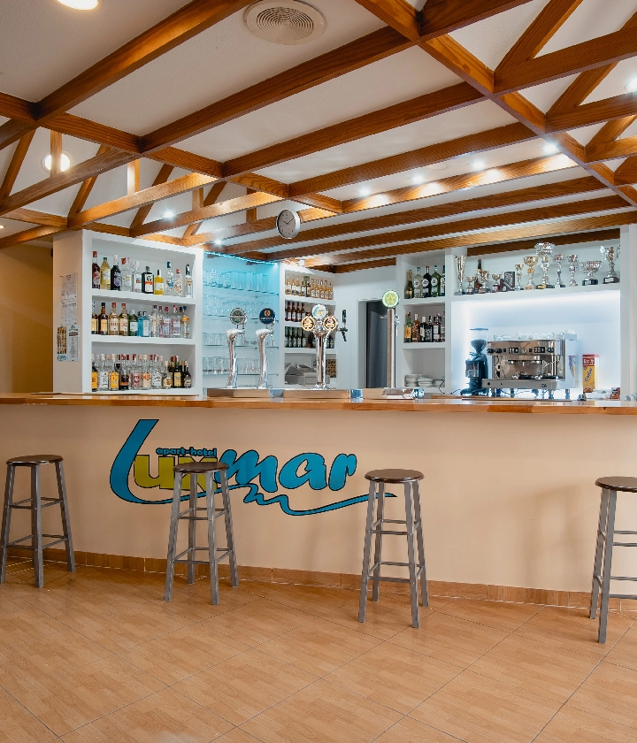 Recepción del hotel con una barra para servir bebidas y taburetes