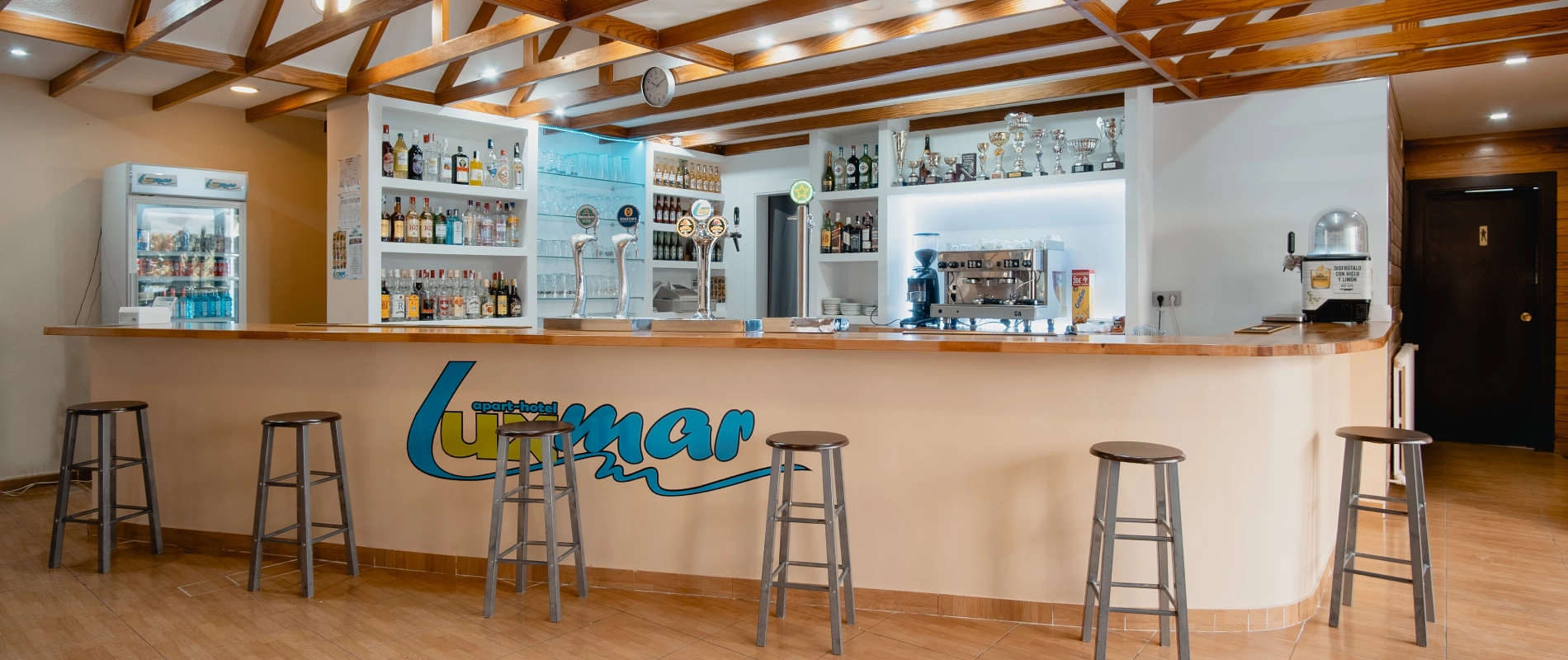 Recepción del hotel con una barra para servir bebidas y taburetes
