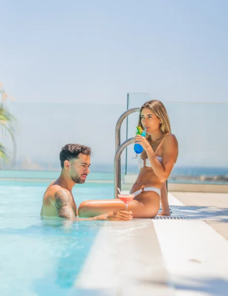 Personas en la piscina disfrutando de bebidas bajo el sol.