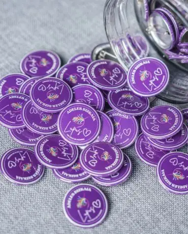 Fichas moradas con diseño de unicornio esparcidas sobre una superficie gris.