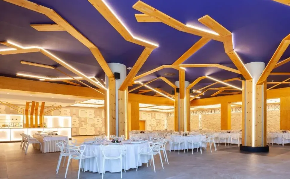 Salón moderno con mesas redondas y techo azul con estructuras de madera que simulan ramas.