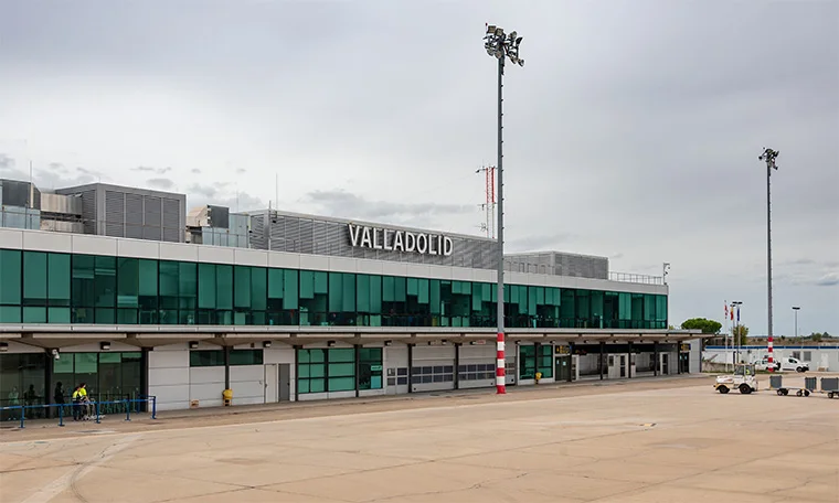Edificio del aeropuerto de Valladolid bajo un cielo nublado, con luces y vehículos en la pista.