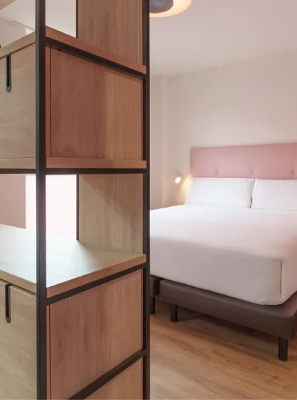 Habitación moderna con cama doble y separador de madera a un lado.