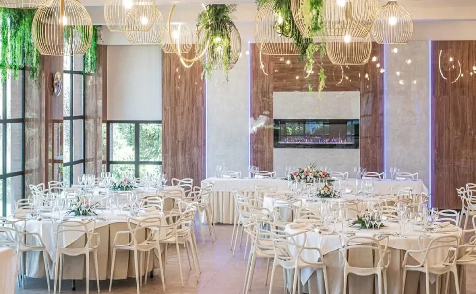 Salón elegante con mesas decoradas y lámparas colgantes de diseño moderno.