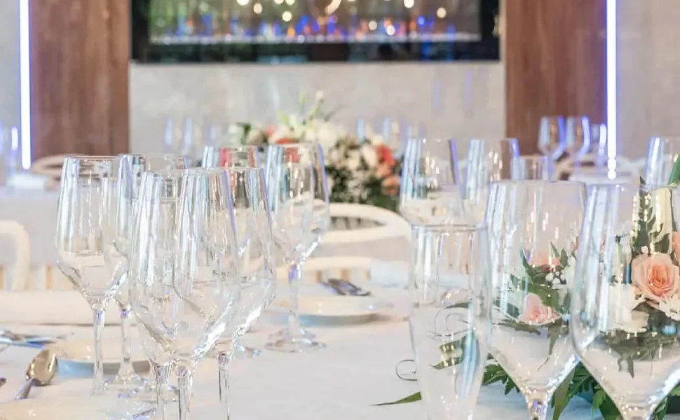 Mesas elegantes con copas y flores decorativas en un evento.