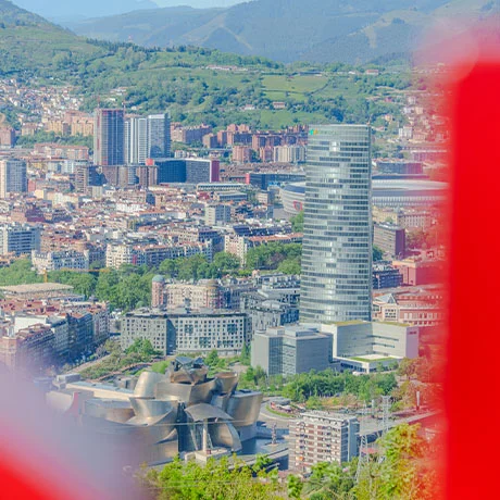 Vista aérea de la ciudad de Bilbao con un edificio alto y el Museo Guggenheim en primer plano.