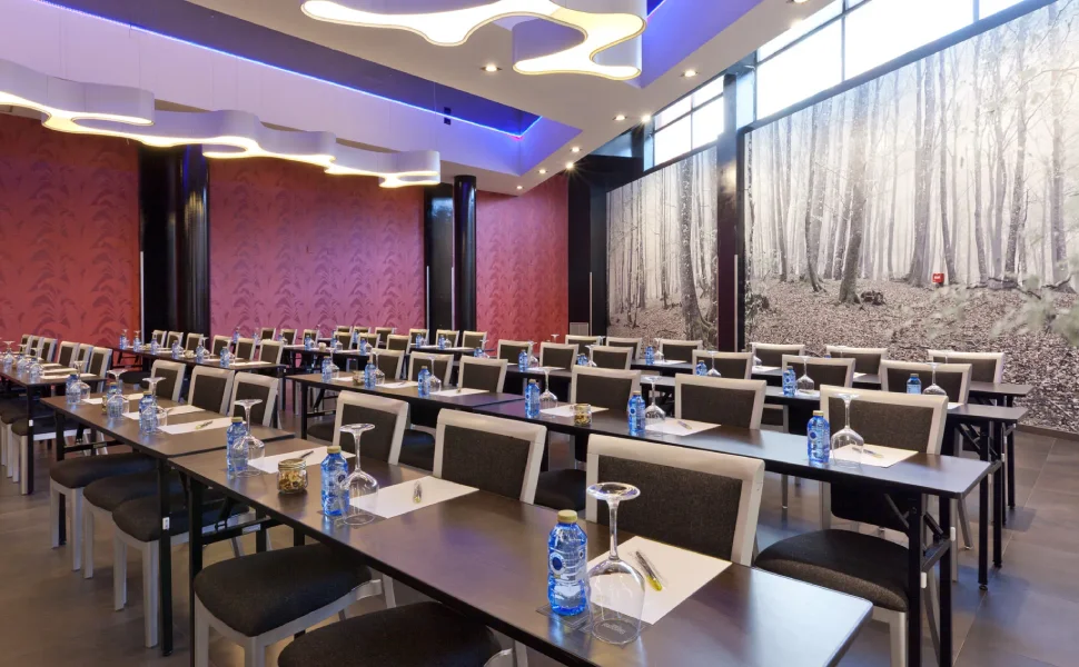 Sala de conferencias con mesas, sillas y botellas de agua. Decoración moderna.
