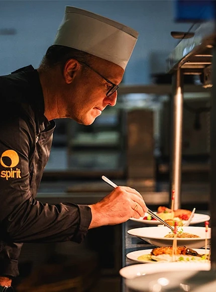 Chef decorando platos con precisión en una cocina profesional.
