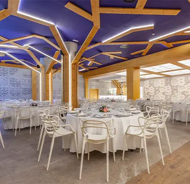 Sala de banquete elegante con mesas redondas y techo moderno de diseño geométrico.