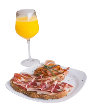 Un plato con tostadas de jamón y salmón junto a una copa de jugo de naranja.