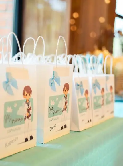 Bolsas decoradas con dibujos de niño y lazo azul sobre una mesa de fiesta infantil.