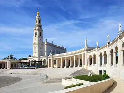 Santuario con torre y estatuas bajo un cielo azul.