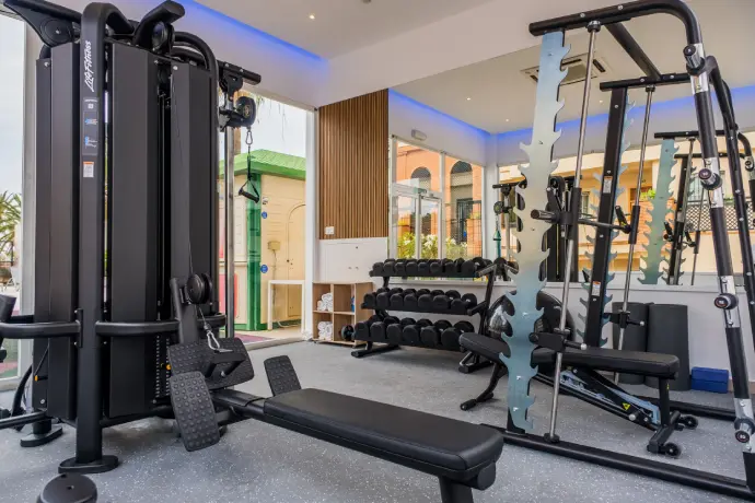 Gimnasio moderno con equipos de ejercicio como bicicleta y máquina de pesas en sala iluminada.