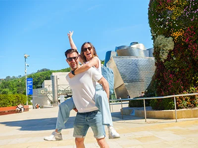 Pareja feliz frente al Museo Guggenheim en un día soleado.