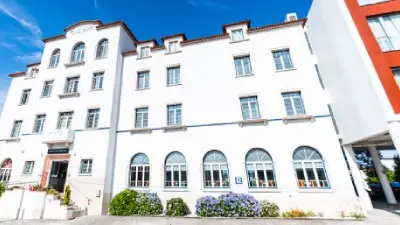 Edificio blanco de varias plantas con ventanas y cielo azul.