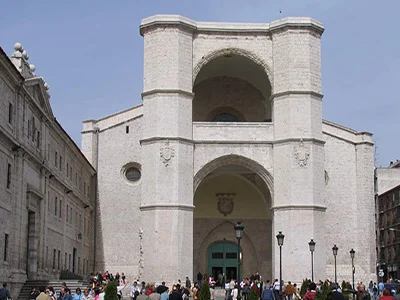Fachada de un edificio histórico con personas alrededor y cielo despejado.