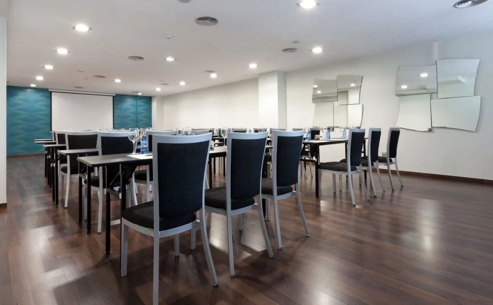 Sala de conferencias moderna con sillas alineadas y mesas negras.