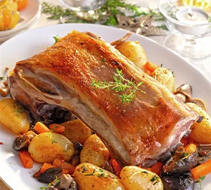 Asado de carne con papas, zanahorias y champiñones, decorado con hierbas.