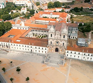 Vista aérea de un gran edificio histórico con techos rojos y un patio central ajardinado.