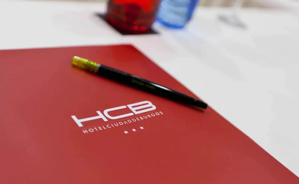 Portafolio rojo del Hotel Ciudad de Burgos con un bolígrafo encima.