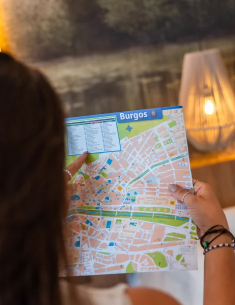 Persona viendo un mapa de la ciudad de Burgos en un entorno acogedor.