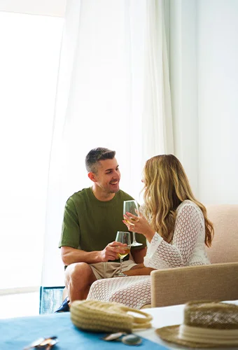 Pareja sonriendo y brindando con copas de vino.