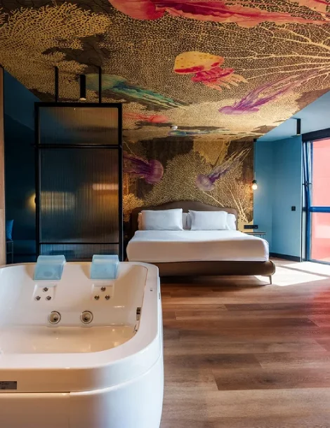 Habitación moderna con cama, jacuzzi y techo artístico colorido.