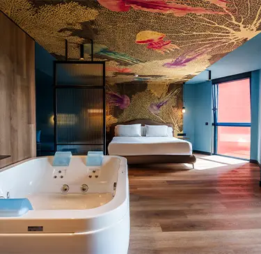 Habitación moderna con jacuzzi, cama grande y techo decorado colorido.