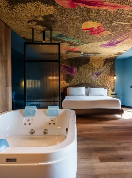 Habitación moderna con bañera, cama y techo colorido.