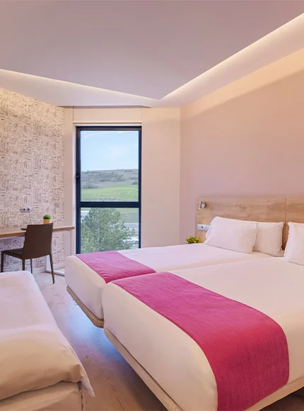 Habitación moderna con dos camas, decoración blanca y rosa, ventana con vista panorámica.