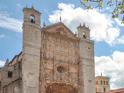 Fachada de iglesia antigua con dos torres, cielo azul y nubes.