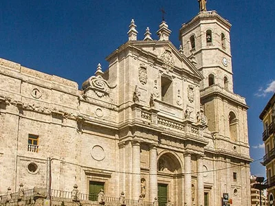 Catedral de piedra con torre y reloj, bajo un cielo azul despejado.