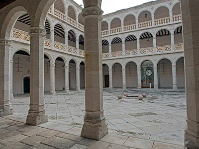 Patio interior con arcos y columnas de un edificio histórico de dos niveles.