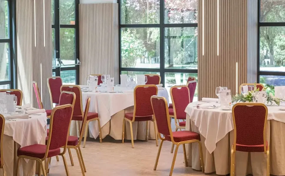 Un salón de eventos elegante con mesas redondas y sillas rojas.