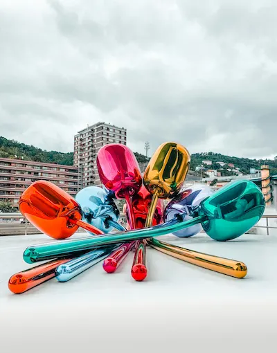 Escultura de tulipanes metálicos de colores brillantes en una ciudad.