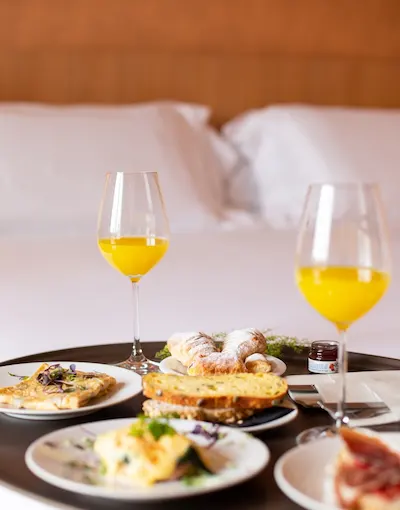 Desayuno con copas de jugo y platos variados sobre una mesa redonda.
