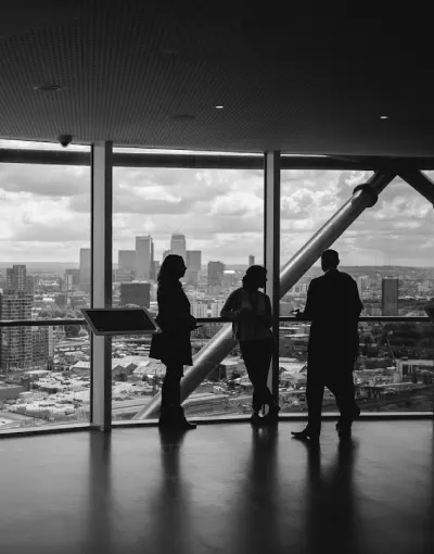 Tres personas de pie junto a una ventana con vista a la ciudad.