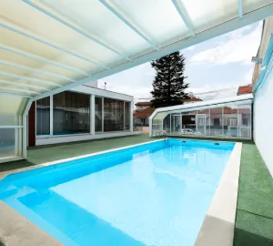 Piscina cubierta con estructura transparente en un entorno residencial.