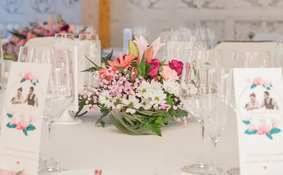 Mesa decorada con flores y copas de cristal en un evento elegante.