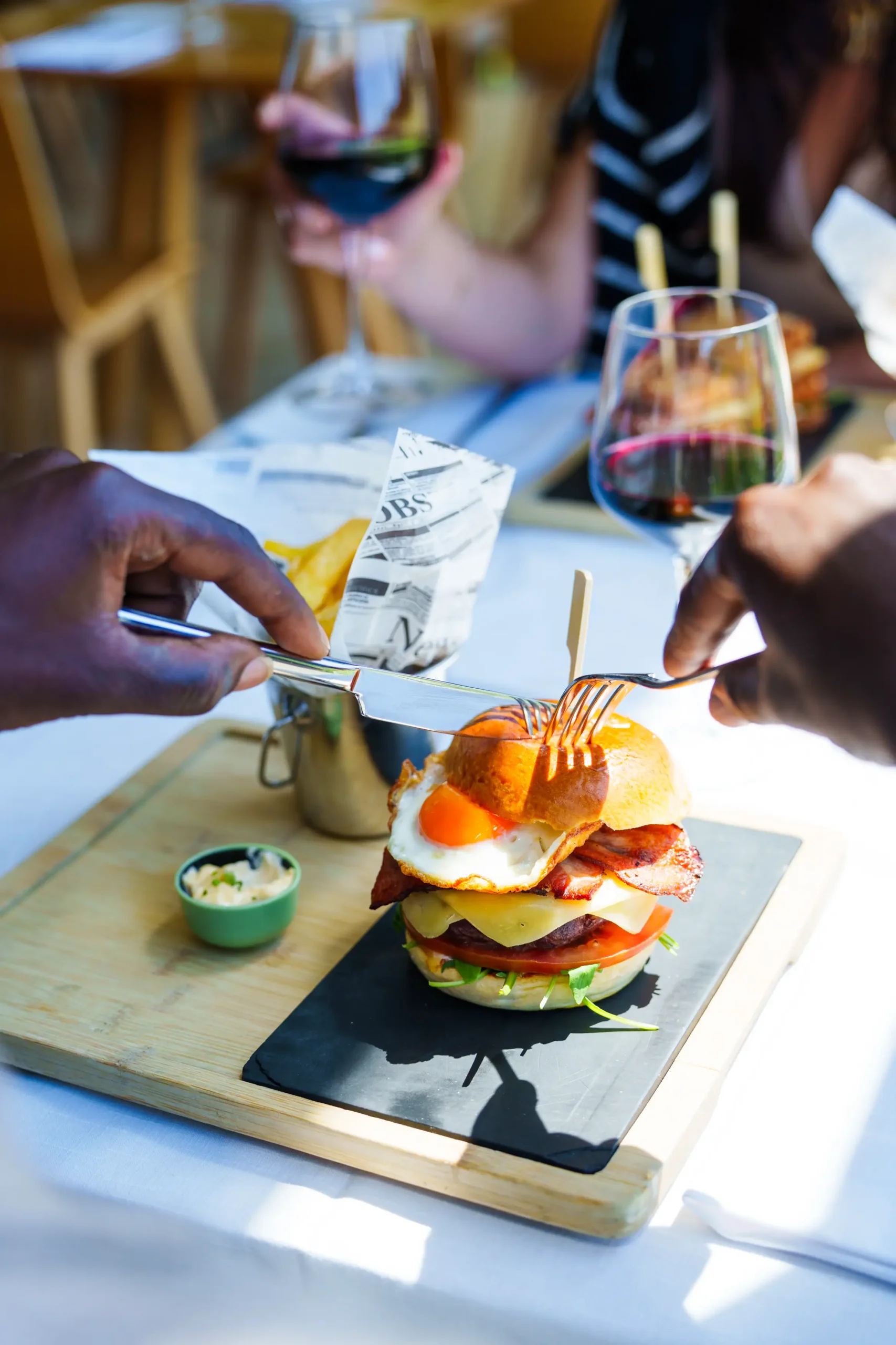 Hamburguesa gourmet con huevo frito, disfrutada con vino tinto en un restaurante.