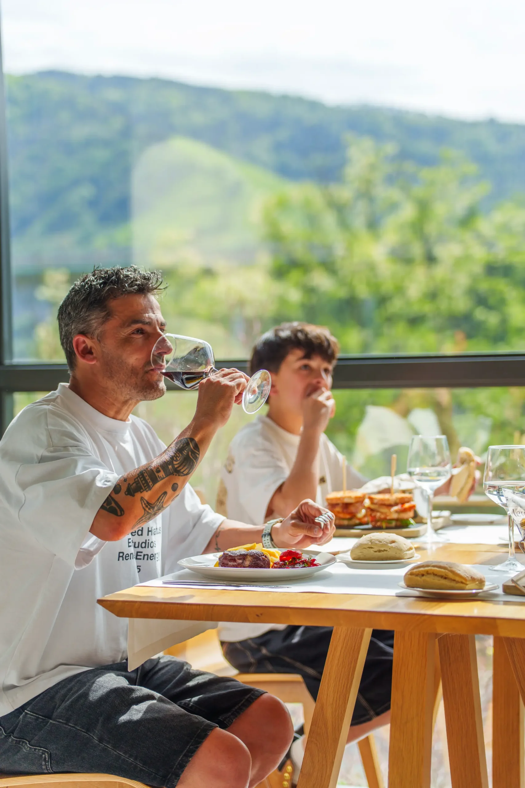 Hombres comiendo y bebiendo en un restaurante con vistas a la montaña.