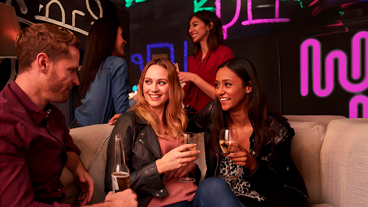 Gente sentada hablando mientras toma algo en una sala de fiestas