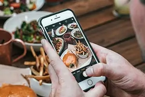 Persona fotografiando comida con un smartphone.