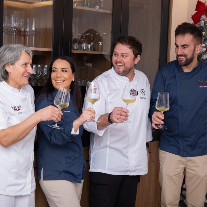 Personas brindando con copas frente a un mueble de cristal.