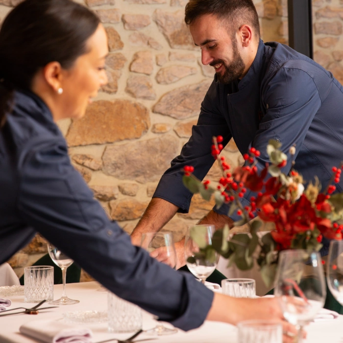 Dos personas preparando una mesa en un restaurante elegante.