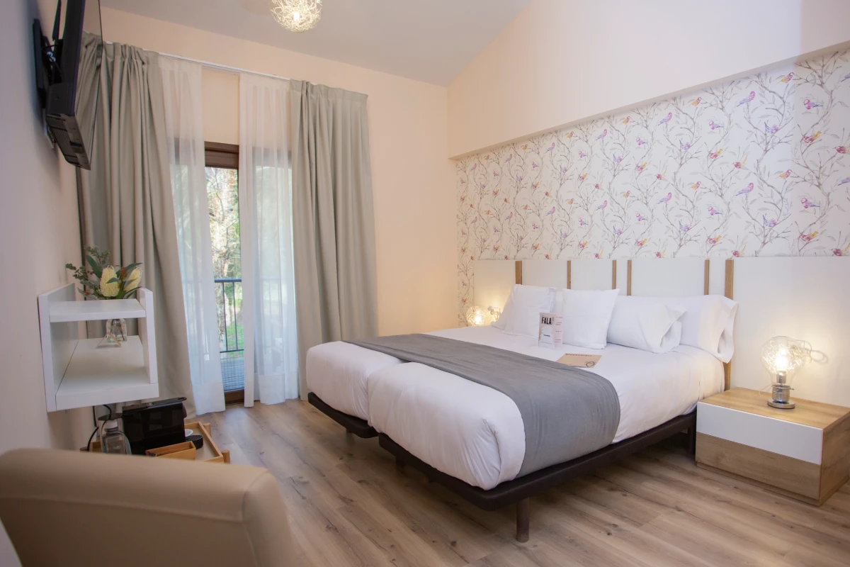 Cama con sábanas blancas y cojines. Fondo de pared floral.