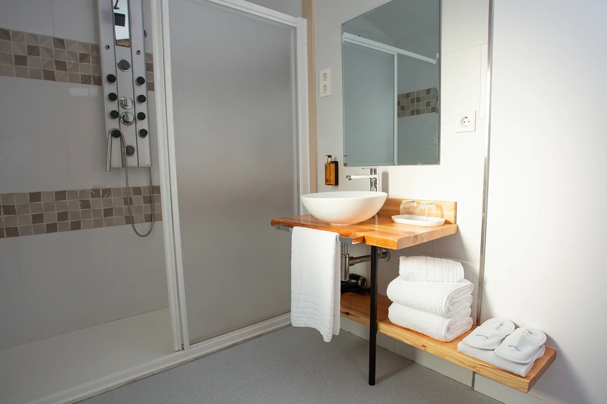 Baño moderno con lavabo de cerámica blanca, espejo ovalado.