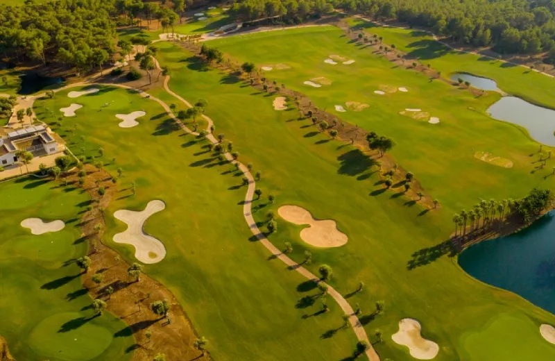 Vista aérea de un campo de golf con lagos, búnkeres y árboles esparcidos.