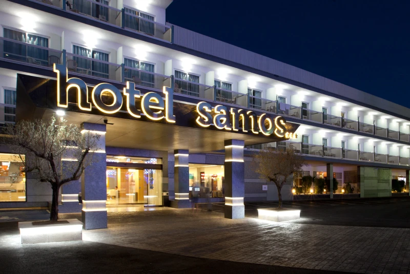 Hotel iluminado por la noche con letrero en la entrada y varios pisos de balcones.